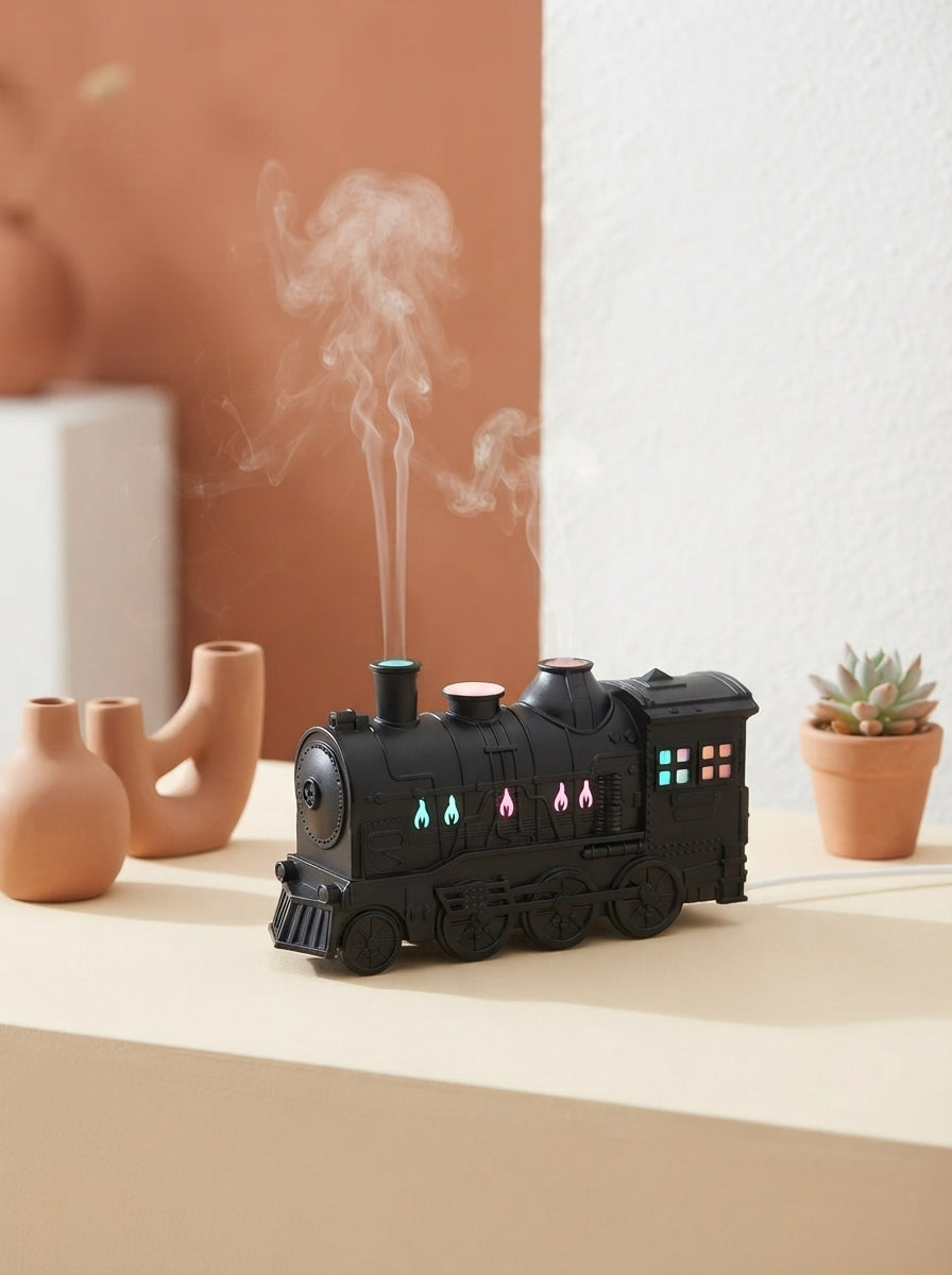 Ultrasonic train aroma diffuser emitting fine mist on a warm cream surface with terracotta accents.